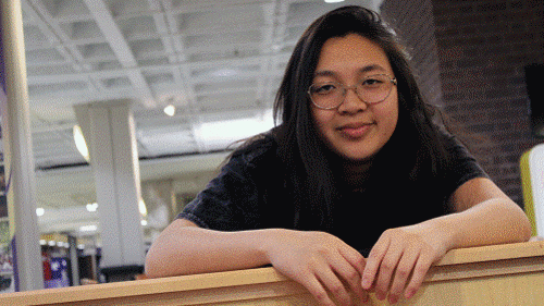 Maria Ly posing with her arms resting on a half wall