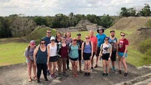 I-O psychology students posing in the jungle with a pyramid in the background while on their international trip