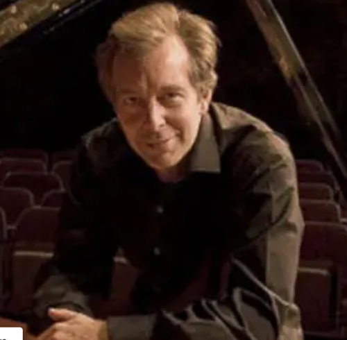 Pianist and composer Gregory Partain posing for a photo in the concert hall at Transylvania University