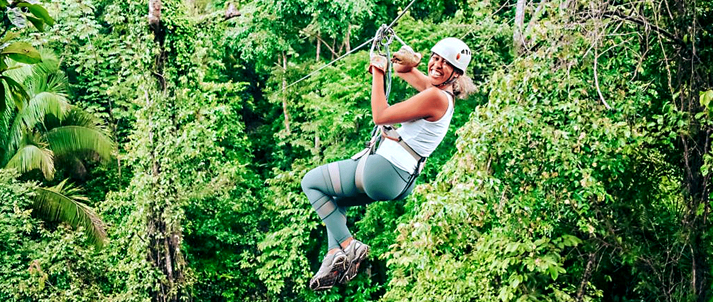 Female student zip-lining into the forest