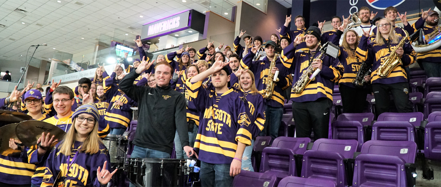 Maverick Machine Athletic Bands posing with musical instruments and throwing up signs of the horns hand gesture