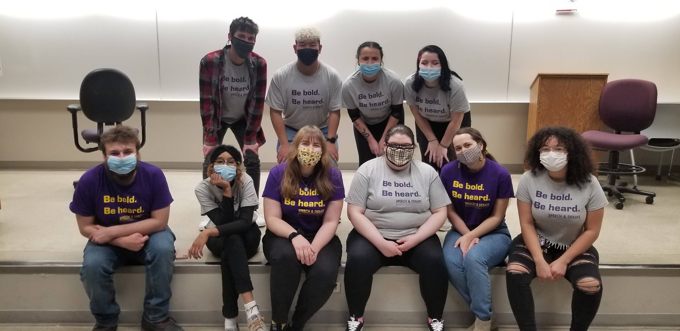 Speech and debate team posing with masks on in the classroom
