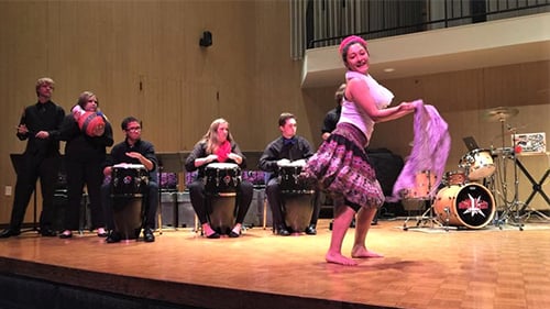 a person dancing on a stage with drums and people in the background