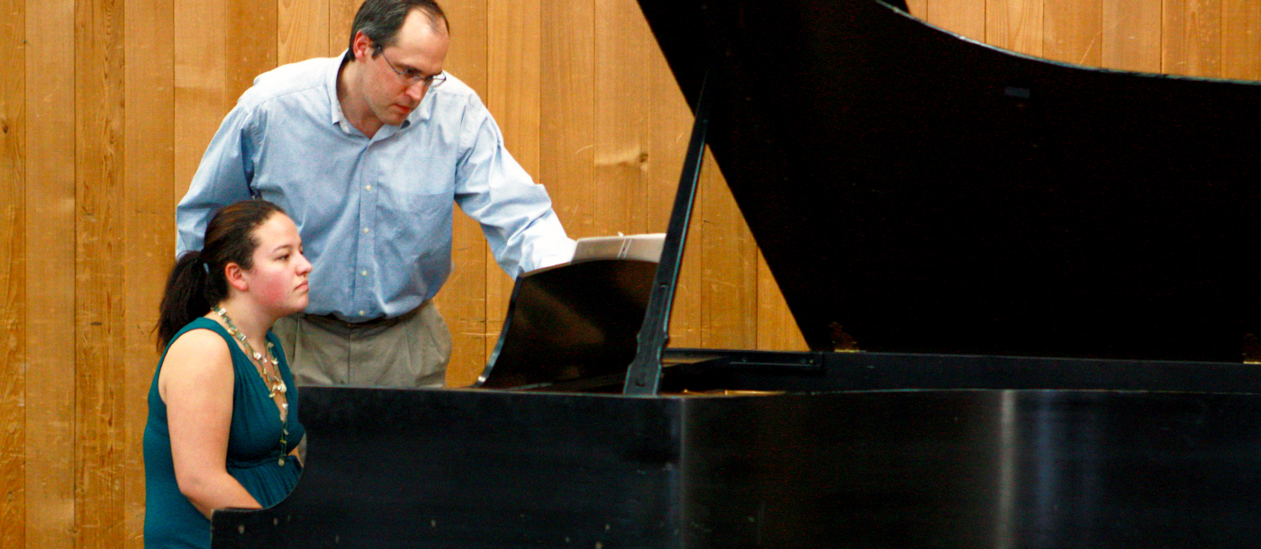 Instructor teaching a student to play piano