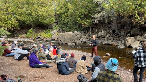 Dr. Andrew Wickert from the University of Minnesota teaching students on the shoreline next to a river at Gooseberry Falls State Park