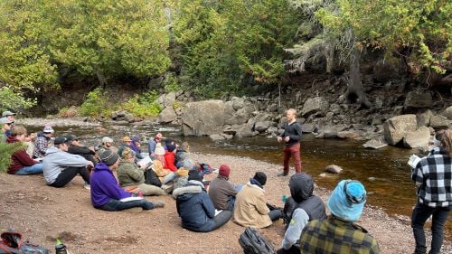 Dr. Andrew Wickert from the University of Minnesota teaching students on the shoreline next to a river at Gooseberry Falls State Park