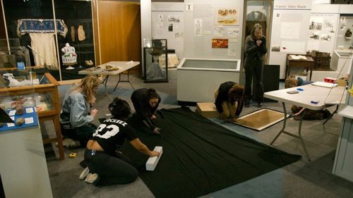 Minnesota State Mankato Department of Art and Design students cutting fabric for an exhibit at the Blue Earth County Historical Society museum