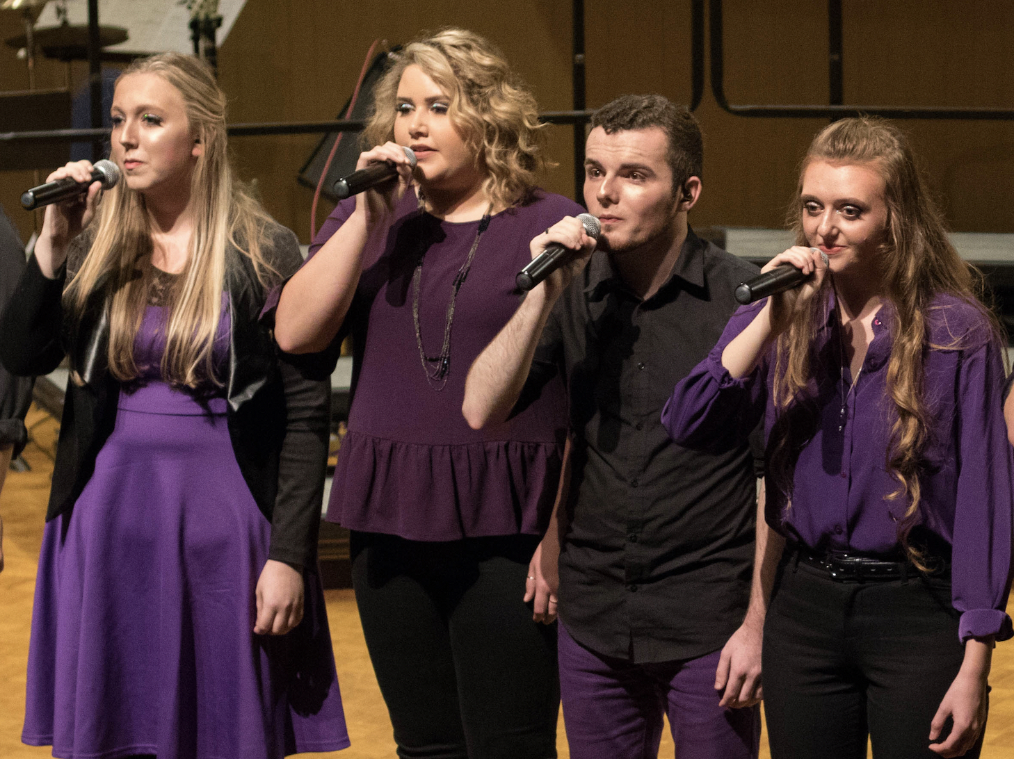 Four singers dressed in purple and black
