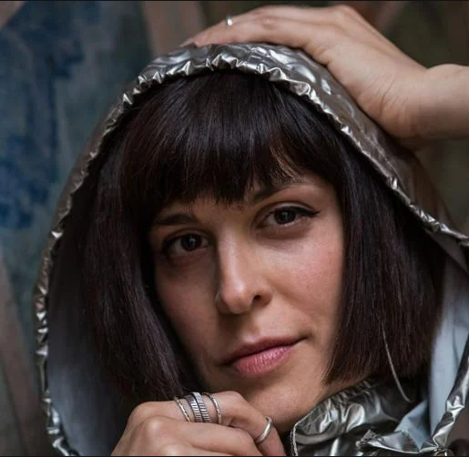 a person with short hair wearing a silver hood