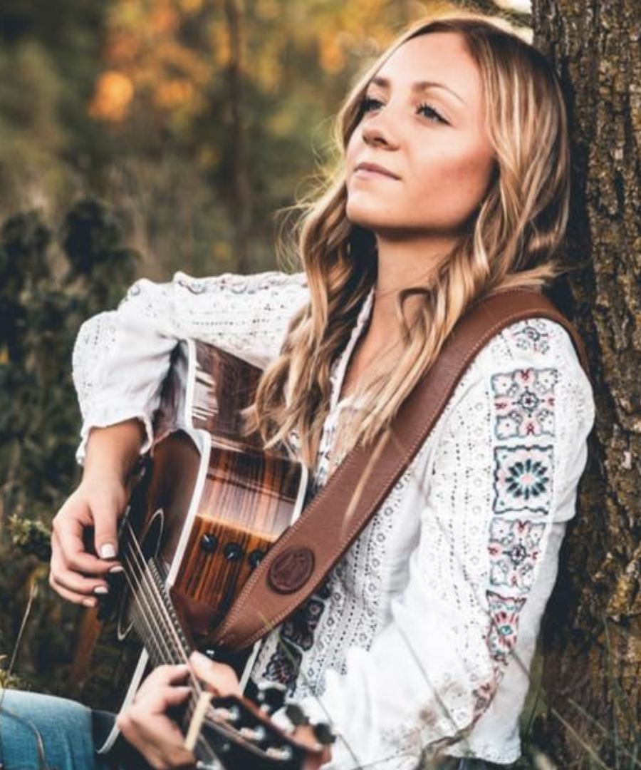 a person sitting next to a tree playing a guitar