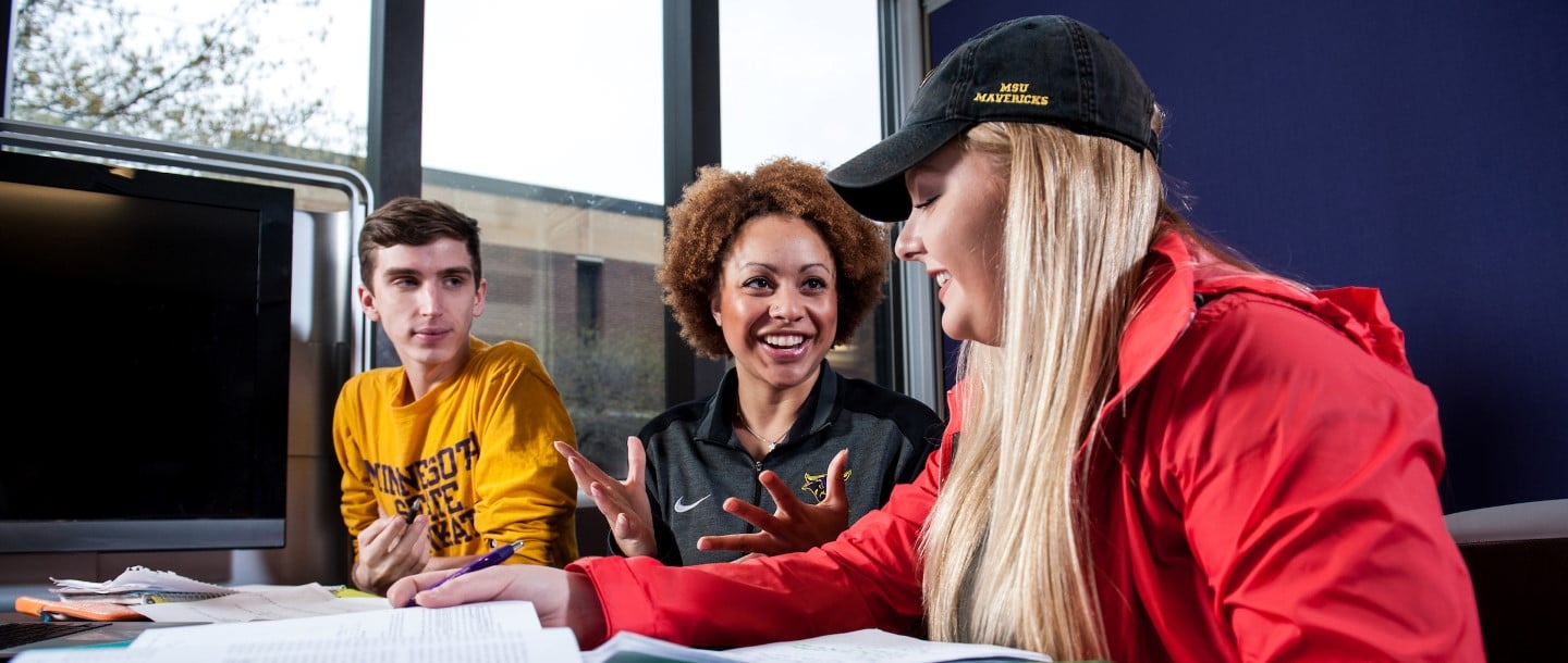 Three Students Talking at a Table