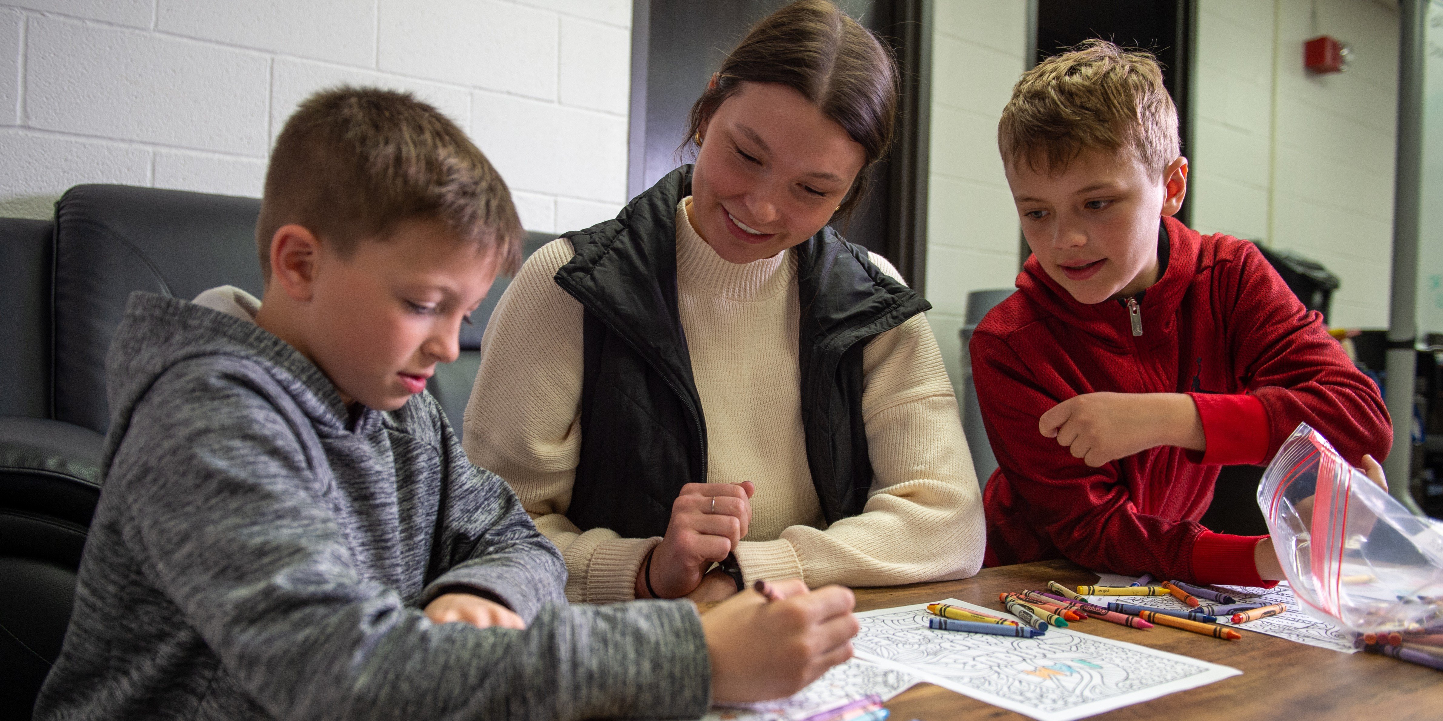 Woman coloring crayons with two boys