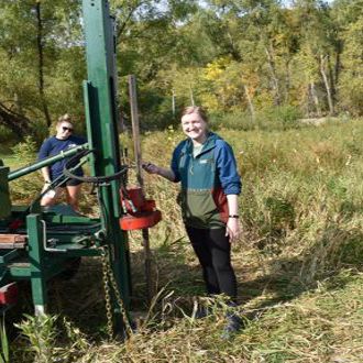 Kenzie Shandonay and another student in a field posing by research equipment