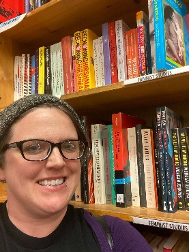 A person taking a selfie infront of book shelf