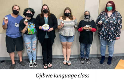 The ojibwe language class students posing in the classroom holding pencil cakes