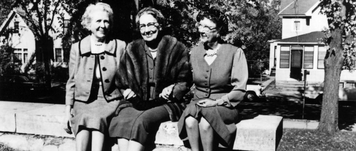 Black and white photo of Maud Hart Lovelace (Betsy, Tacy, Tib) sitting on a block wall from 1961