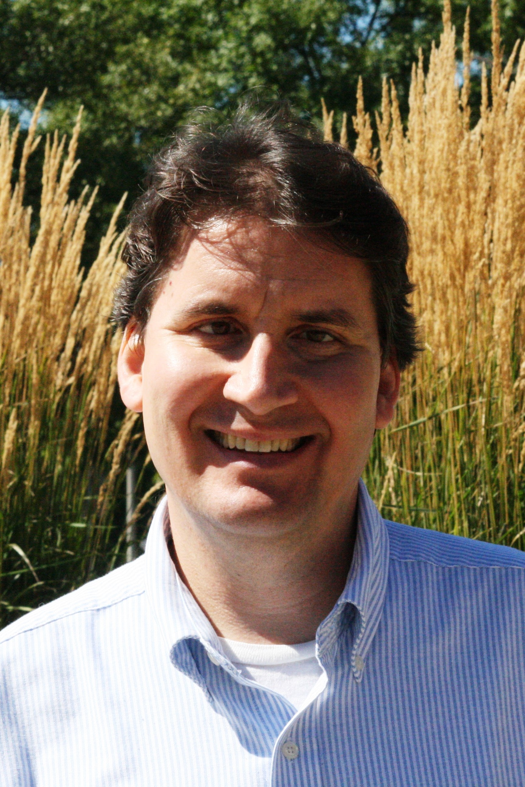 a person smiling in front of tall grass