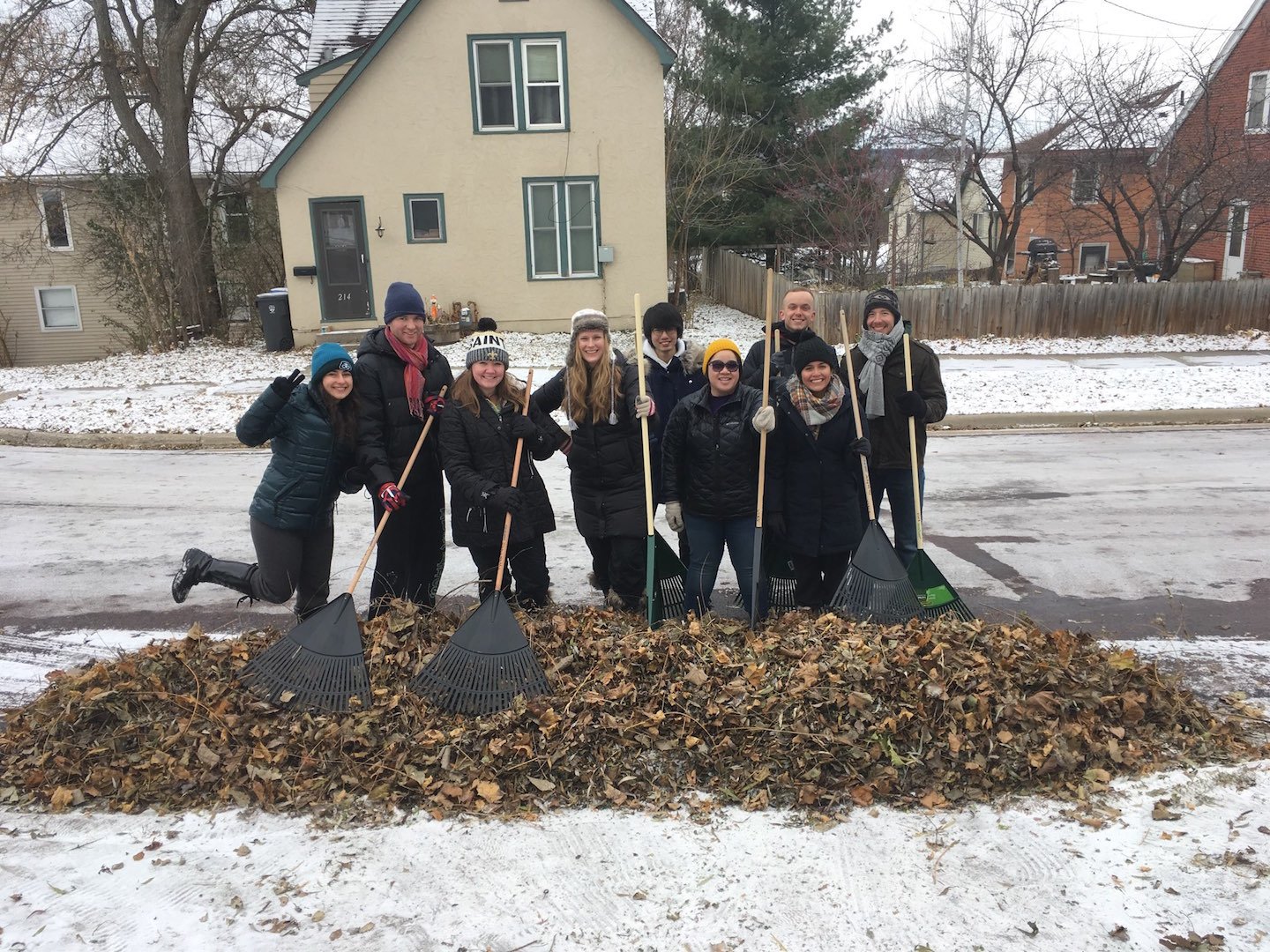 a group of people holding rakes in front of a house