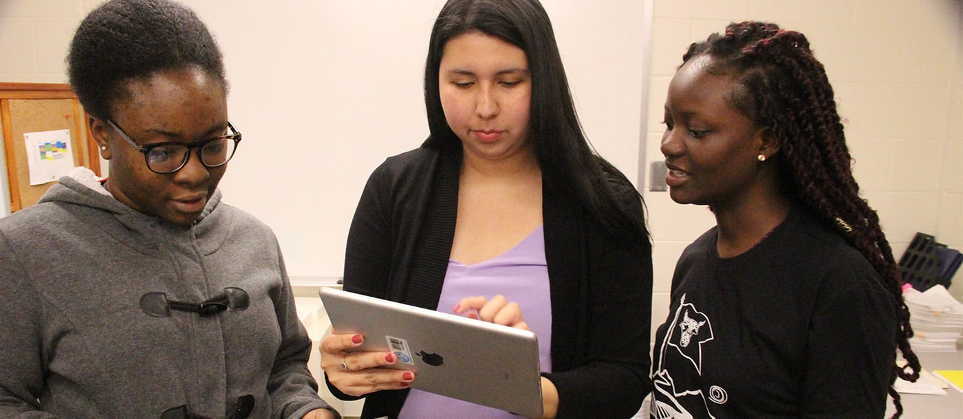 3 female students looking at a tablet