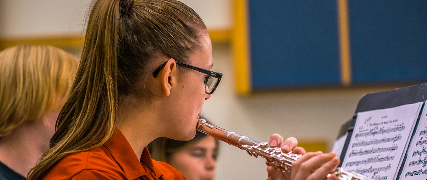 Student playing flutes by looking at her music books
